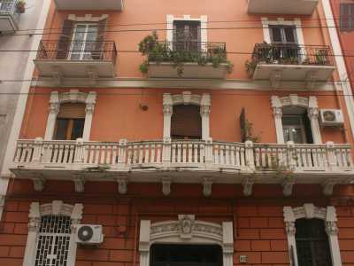 Foto 9. Ripercorriamo per un breve tratto via Manzoni per arrivare in via Crisanzio. Scopriamo qui un brillante palazzo arancione, il cui balcone al primo piano mostra una bellissima balaustra in pietra e le lesene delle persiane decorate